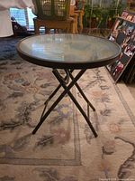 Small round glass top folding table with metal X-legs