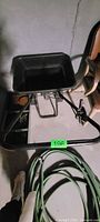 Overall view of black plastic hopper broadcast spreader on metal frame