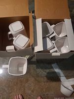 Two boxes containing ten white square cups