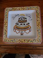 Front of square ceramic plate showing birthday cake graphic and decorative border