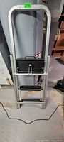 Full view of folded aluminum two-step ladder with black steps