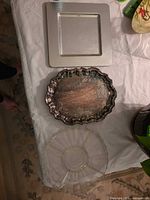 Square metal tray, ornate silverplate tray, round glass platter on table