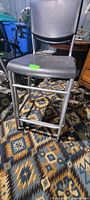 Full view of one stool showing metal frame, footrest, and black seat/back