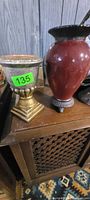 Gold pedestal urn and red urn vase on table