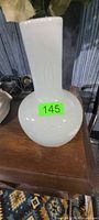 Front view of opaque white glass vase on table
