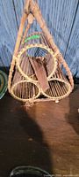 Front view of triangular bamboo wine rack showing three circular bottle compartments