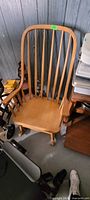 Front three-quarter view of the wooden rocking chair showing spindle back, seat, armrests and rockers