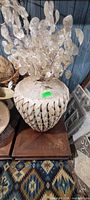 Bulbous woven rattan vase with diamond cut-outs holding dried lunaria stems