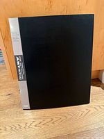 Front view of one black Itoya Art Profolio book standing upright