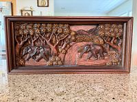 Full view of carved wooden wall panel in frame