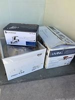 Three boxed items: Glacier Bay faucet, white box light fixture, For Living ceiling fan