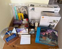 Overview of all items on tabletop with visible phone box, photo frame box, clock, trackpad, picture cards, mousepad, Mozart CD and office supplies