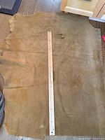 Full view of large tan leather hide with yardstick for scale