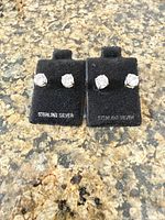 Front view of two pairs CZ stud earrings on black cards