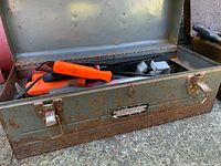 Grey-green toolbox open showing orange-handled tools and socket set
