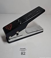 Front perspective of guitar pick punch showing handle, base and logo