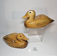 Two carved wood ducks, one upright on acrylic riser, one resting, lot overview