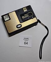 Front view of Kodak Disc 3100 camera showing lens cover, flash, shutter button, Kodak logo and attached wrist strap