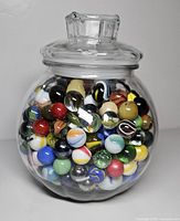 Jar filled with assorted marbles, lid on