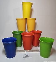 Front view of eight assorted-colour Tupperware tumblers standing on display block