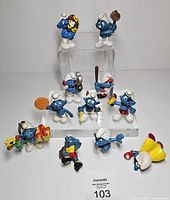Group shot of all eleven Smurf figurines on two clear risers and table surface