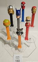 Front view showing heads of all seven PEZ dispensers on clear stand