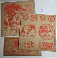 Three printed wood panels stacked showing various red designs