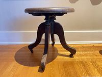 Side view of stool showing legs, casters and metal adjustment mechanism