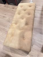 Top view of beige tufted upholstered bench showing button pattern and fabric condition