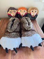 Slippers pair with three character plush pillows on table
