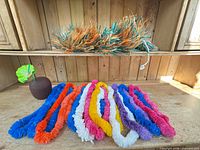 Overview of multicolored leis, raffia skirt bundle and coconut cup