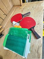 Two Matrix paddles, two balls, shuttlecock, folded green net