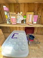 Shelf with cupcake carrier, glass dishes, water bottle, packaged party supplies