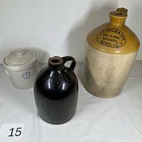 Front view of three stoneware pieces: lidded crock, black jug, two-tone Job Wells & Son jug