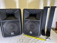 Front view of both speakers with wall brackets and tape measure for scale