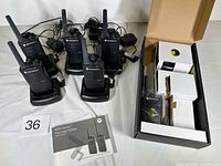 Six radios on charging docks with power adapters, boxed unit, user guide visible