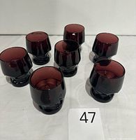 Seven ruby glasses arranged on white surface with lot card 47; shows overall style and color