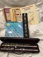 Overall lot showing Yamaha flute in case, Hall crystal flute with instructional booklet, and stack of sheet music books