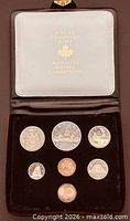 Closed clamshell case opened showing all seven coins in velvet insert