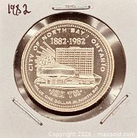 Obverse of 1982 North Bay Ontario trade dollar in flip showing skyline design and centennial dates