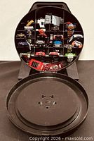 Front view of open round carry case showing die-cast vehicles inside and detached lid