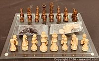 Full set on glass board showing chess pieces and bagged checkers