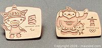 Two bronze-tone lapel pins side by side showing mascot engravings