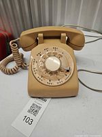 Full view of beige rotary dial telephone with handset, coiled cord, and line cord
