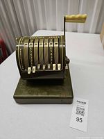 Front angled view of Paymaster check writer showing keys, drum and base