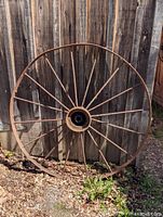 Full view of wagon wheel leaning against wood wall
