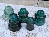 Group of five glass insulators displayed on lace cloth