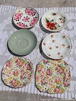 All six saucers laid out to show variety of patterns and shapes