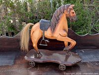 Full view of carved wooden horse on wheeled base