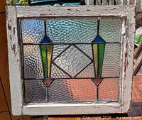 Front view of entire stained glass window showing geometric design and pine frame